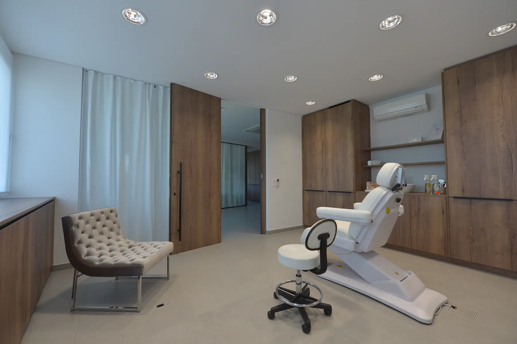 Helles Behandlungszimmer mit weissem Behandlungsstuhl und Holzeinbauten